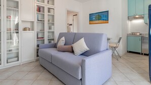 A living room with a sofa, a dining area with a chair, and a kitchen with cabinets and appliances. - Casapa - Parking - Sanremo (Sanremo)