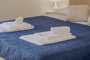 A neatly made bed with a blue quilt and white towels. - CASAPA - Parcheggio - Sanremo (Sanremo)