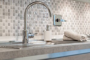 A modern bathroom with a chrome faucet, a soap dispenser, and a towel on the counter.
