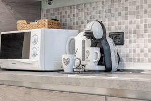 A kitchen with a microwave, coffee maker, and a basket on the counter. - IL NIDO - Centro - Ariston (Sanremo)