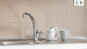 Een keuken met een RVS spoelbak, een wit aanrechtblad en een backsplash met een ruitpatroon.