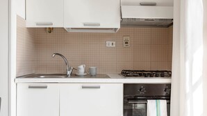 Een moderne keuken met witte kasten, een roestvrijstalen spoelbak en een gasfornuis met oven.