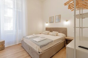 A modern bedroom with a bed, bedside tables, a wardrobe, and a window with curtains.
