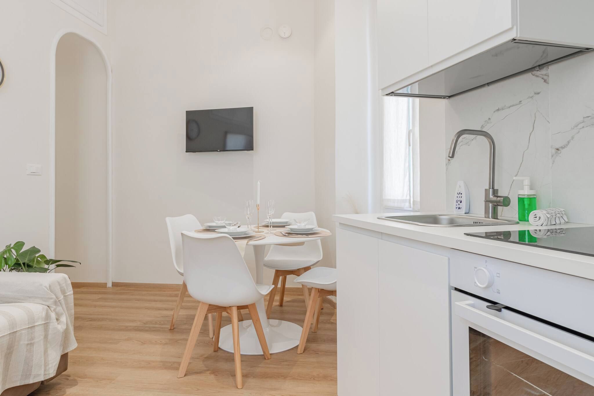 A modern kitchen with white cabinetry, a built-in oven, and a stainless steel sink.
