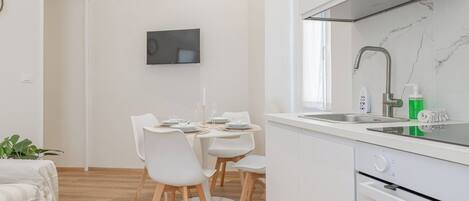 A modern kitchen with white cabinetry, a built-in oven, and a stainless steel sink.
