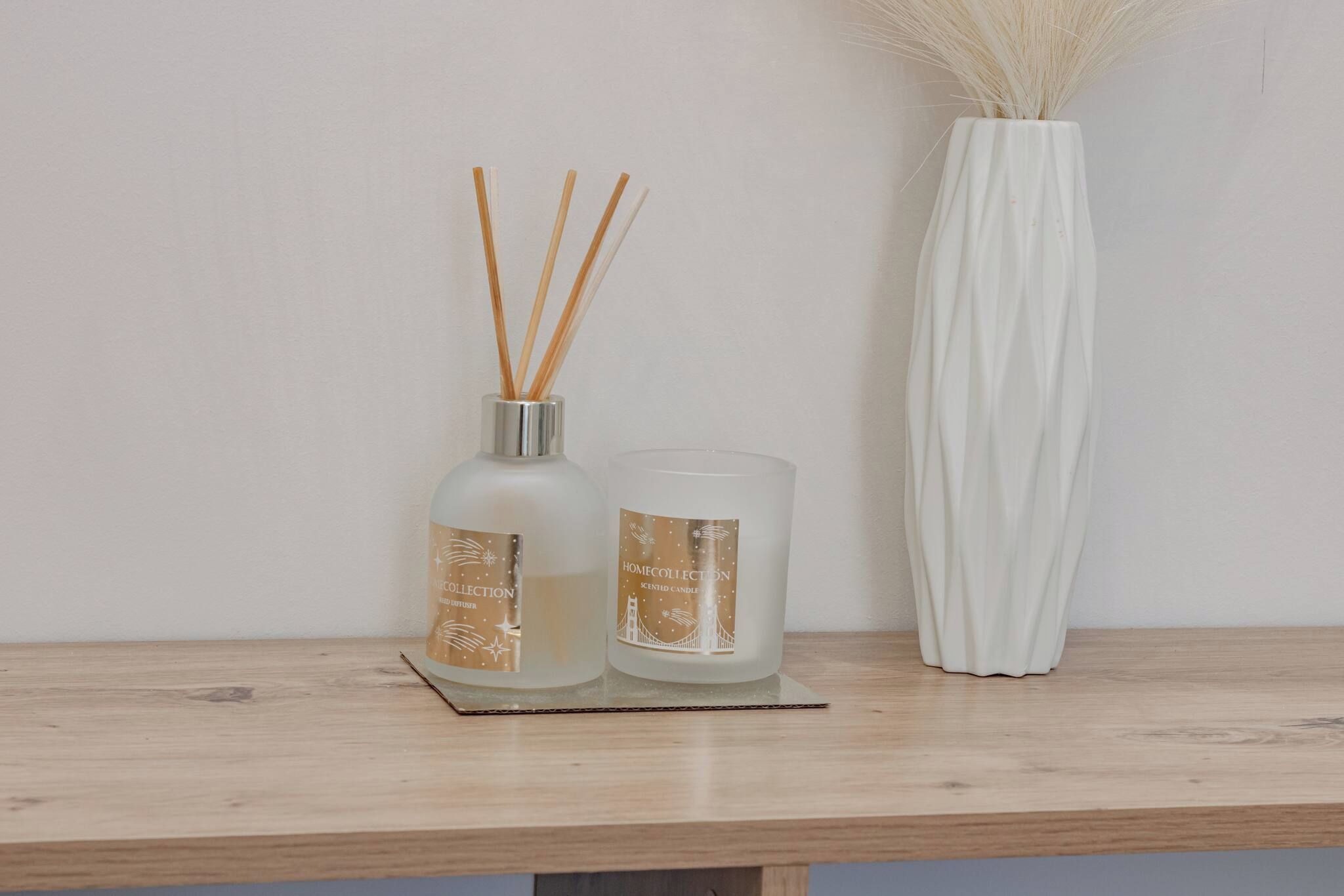 A wooden shelf with two glass diffusers and a white vase with dried reeds.
