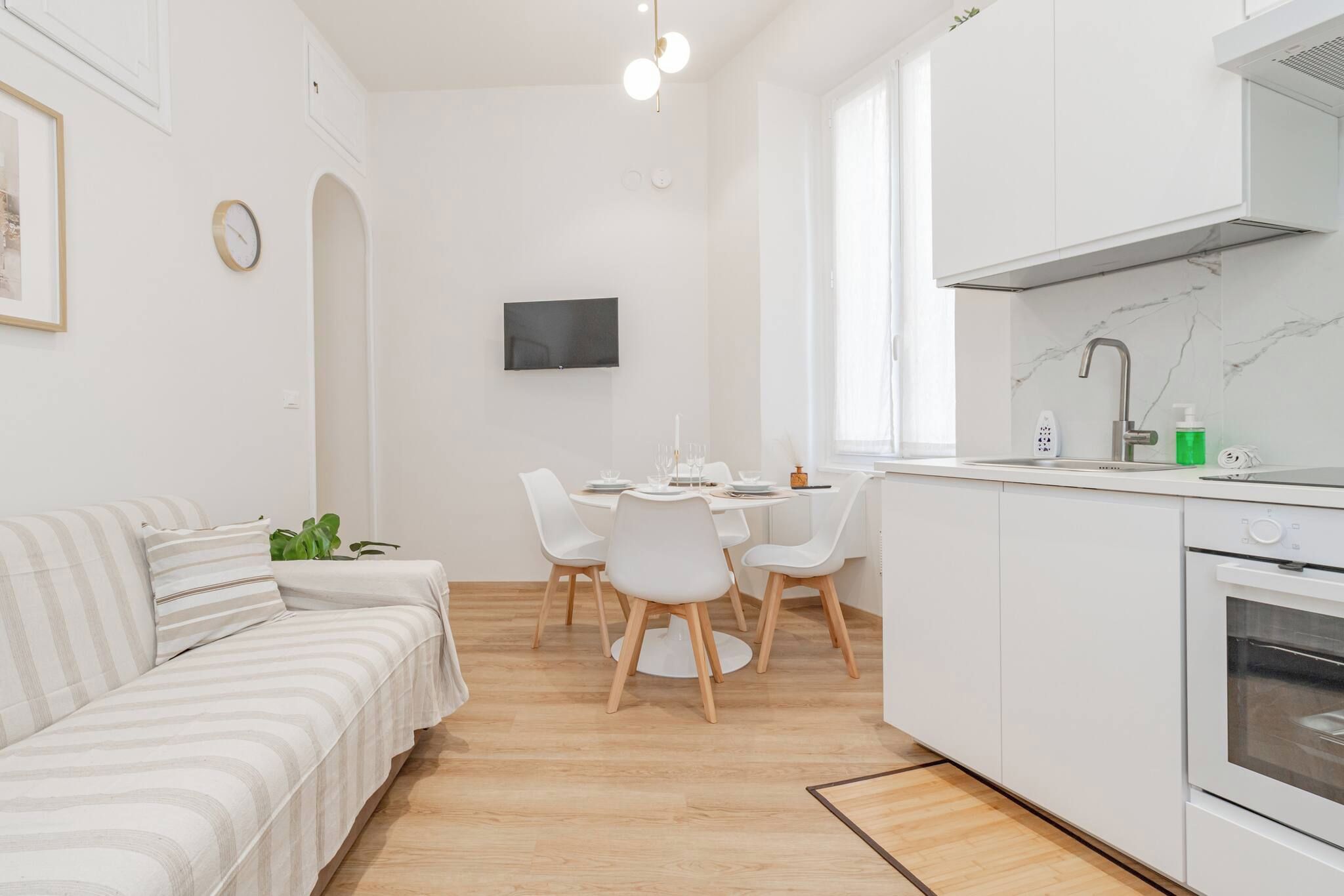 Een moderne, minimalistische woonruimte met een bank, eettafel en keuken.
