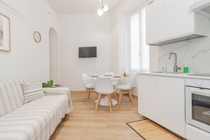 A modern, minimalist living space with a sofa, dining table, and kitchen area.