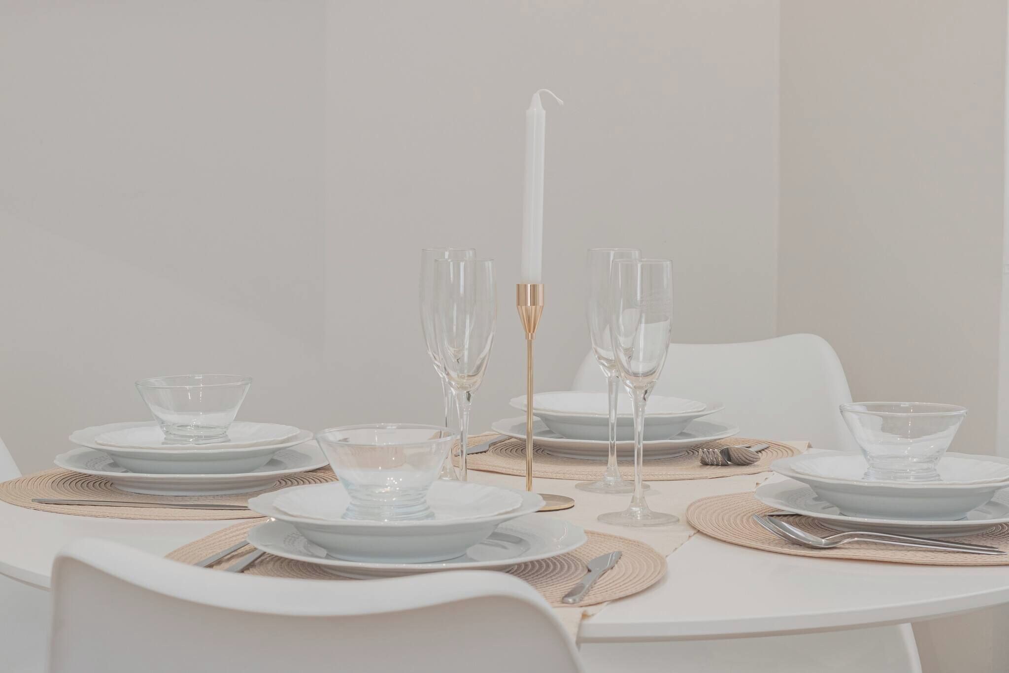 A table set for a meal with clear glassware, plates, and a candle.