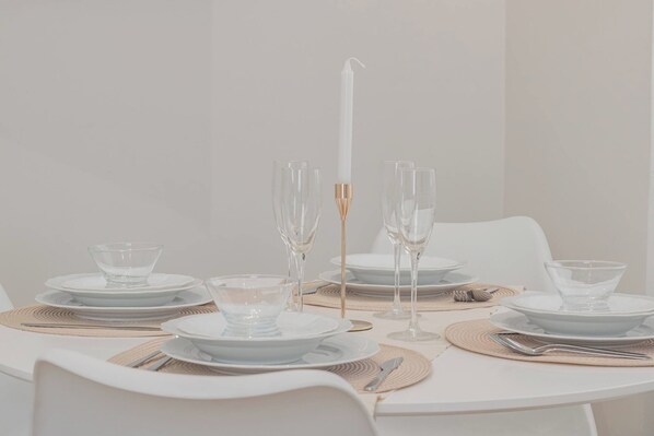 A table set for a meal with clear glassware, plates, and a candle.