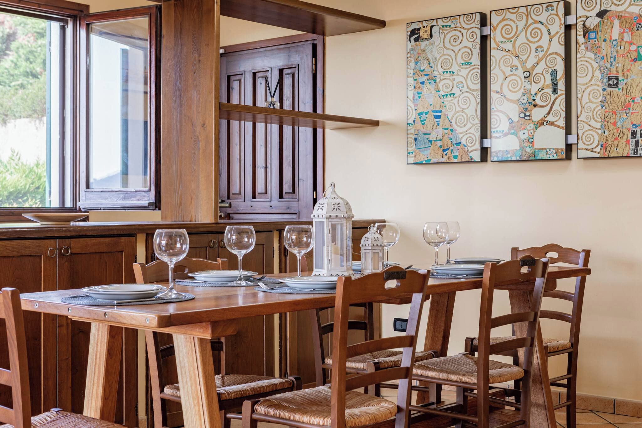 A dining area with a wooden table set for four, surrounded by wooden chairs with woven seats.