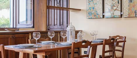 Un comedor con una mesa de madera dispuesta para cuatro personas, rodeada de sillas de madera con asientos de mimbre.