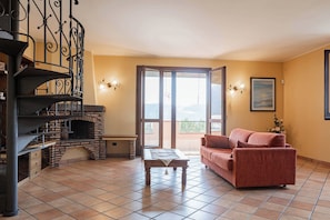 Una sala de estar con chimenea, un sofá, una mesa de comedor y una escalera.