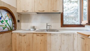 Eine Küche mit Holzausstattung, einer Spüle aus Edelstahl und einem Fenster mit Blick auf schneebedeckte Bäume.