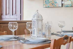 A dining table set with plates, cutlery, and wine glasses, with a decorative lantern in the center. - OASI SERENA - Parcheggio-Giardino (Liguria)
