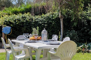 An outdoor dining table set with chairs, a lantern, and a fruit bowl.