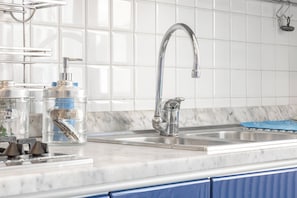 A kitchen with a stainless steel sink, a faucet, and a marble countertop.