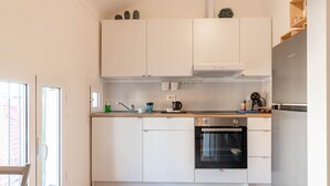Et moderne køkken med lyse skabe, et rustfrit stål køleskab og en indbygget ovn.