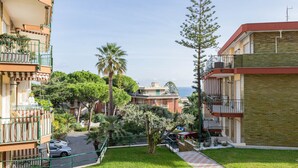 A residential area with a grassy courtyard, a palm tree, and a view of the sea. - Silver House in Sanremo (Sanremo)
