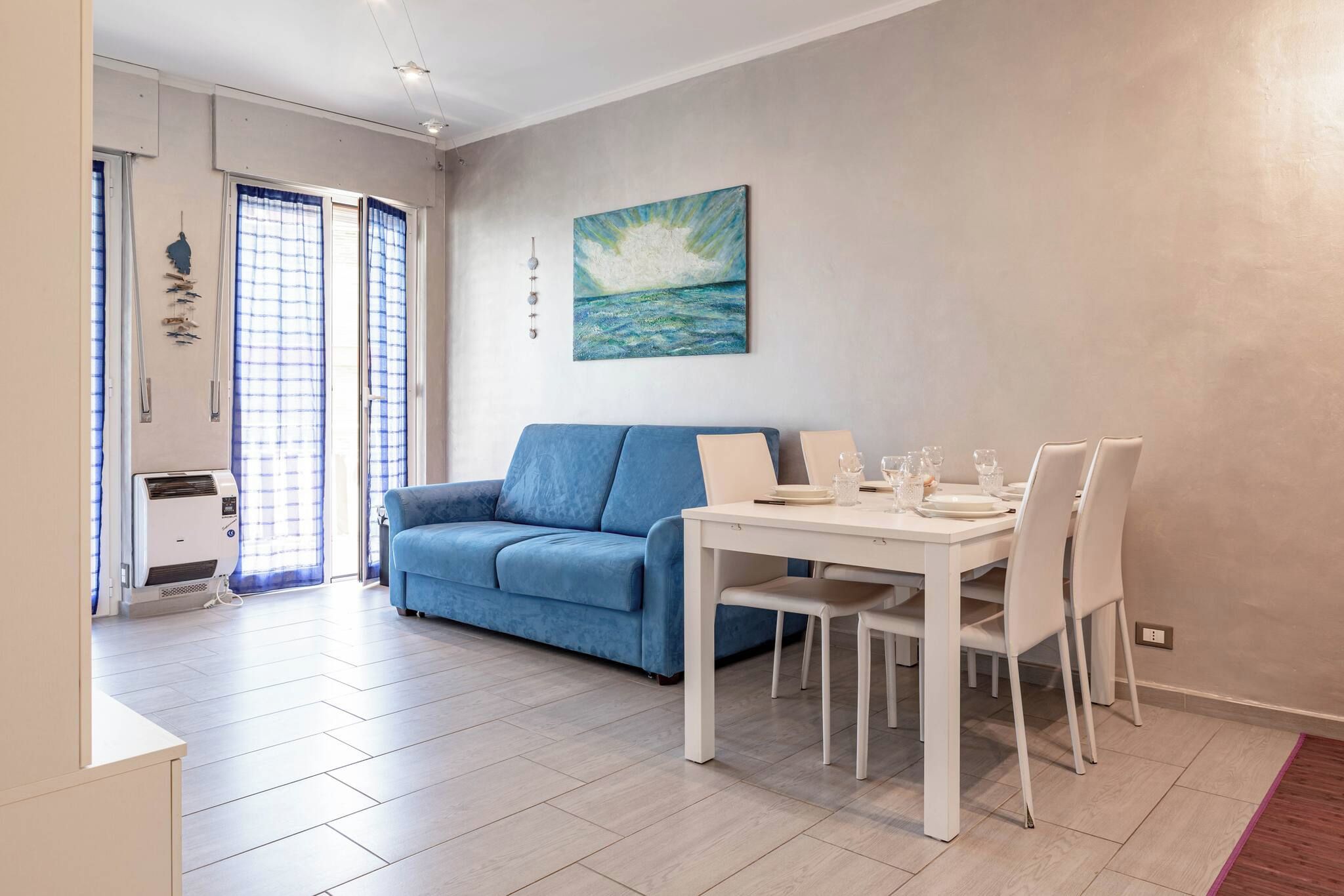 Un salon avec un canapé bleu, une table à manger avec des chaises et un tableau accroché au mur.