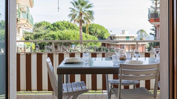 A balcony with a table set for dining, chairs, and a view of the surrounding area. - Silver House in Sanremo (Sanremo)
