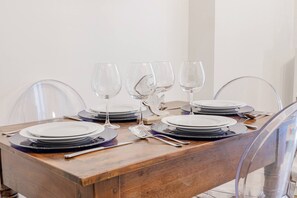 Une table à manger dressée avec des assiettes, des couverts et des verres à vin.