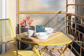 A yellow metal table with a white bowl, a blue glass, and a wooden board. - SUITE LA MER - Sanremo - Spiagge (Sanremo)
