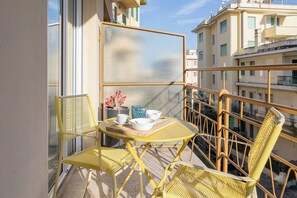 A balcony with yellow chairs, a table, and a small potted plant. - SUITE LA MER - Sanremo - Spiagge (Sanremo)