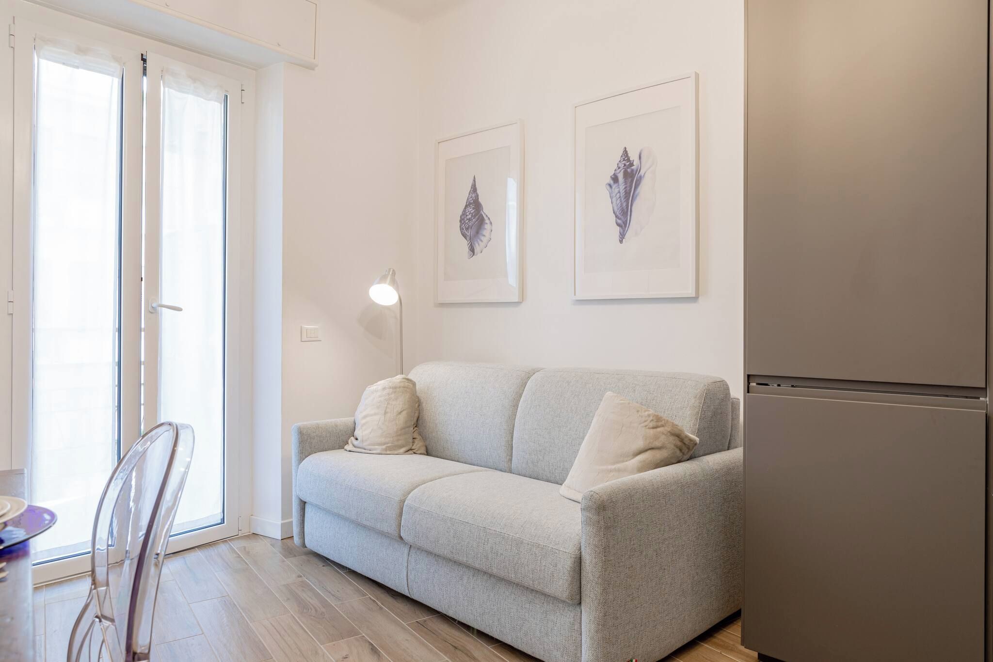 Ein Wohnzimmer mit einer Couch, zwei Kissen, einem Tisch mit Stühlen und einem Kühlschrank.