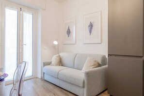 Un salon comprenant un canapé, deux coussins, une table avec des chaises et un réfrigérateur.