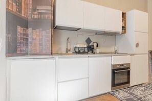 A compact kitchen with white cabinetry, a built-in oven, and a coffee maker. - THE KINGDOM'S APARTMENT - Centro - Sanremo (Sanremo)