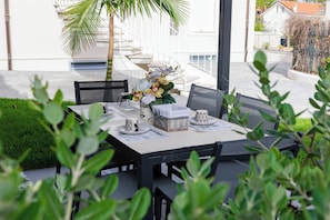 Un área de comedor al aire libre con una mesa lista para dos personas, rodeada de follaje.