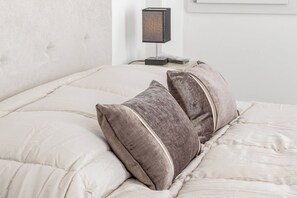 A bed with a beige quilted cover and two pillows with a textured fabric and a contrasting trim. - VILLA MIA - Giardino-Parcheggio (Sanremo)