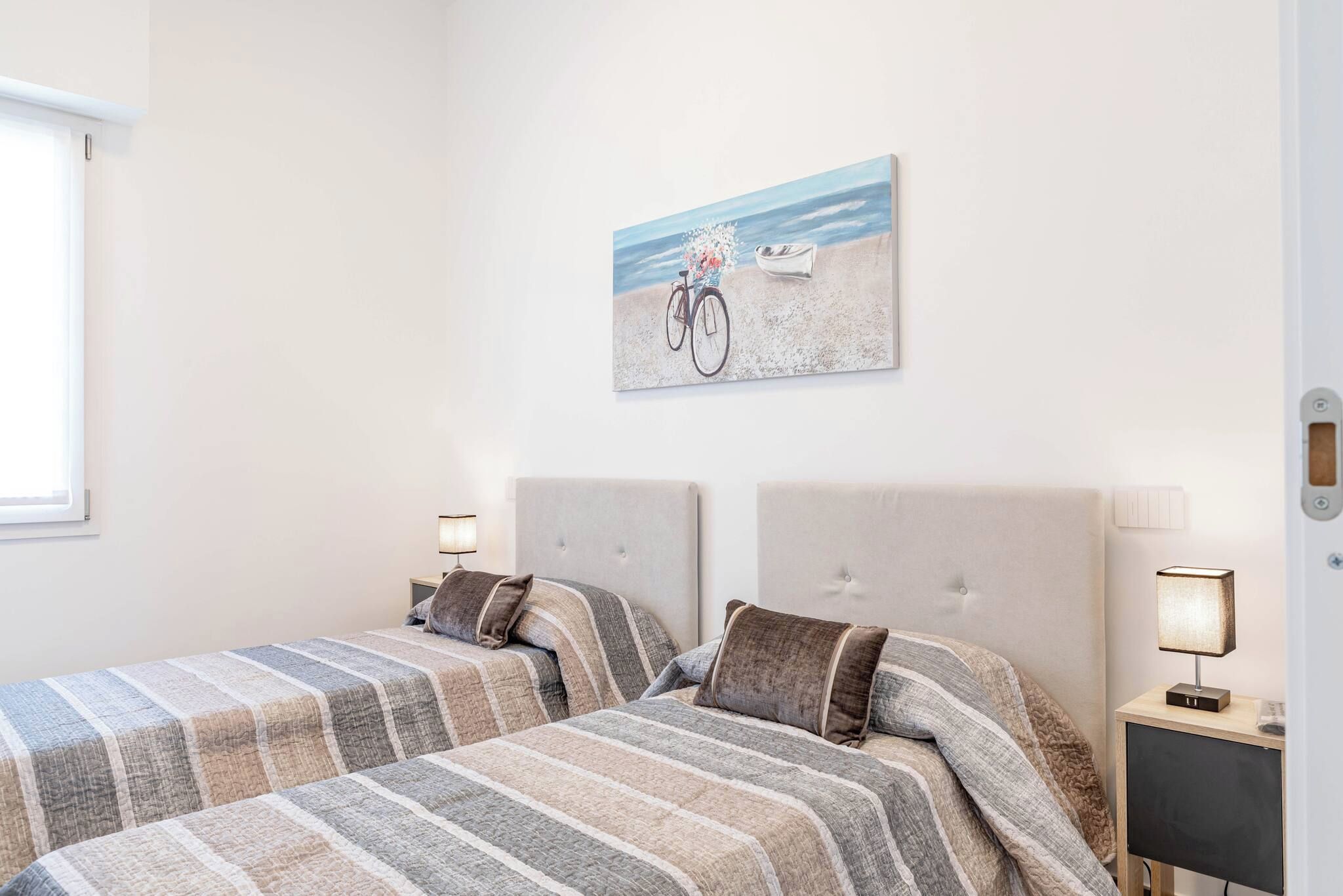 Une chambre avec deux lits, un tableau représentant un vélo accroché au mur et des lampes de chevet.