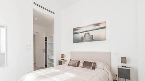 Ein modernes Schlafzimmer mit einem großen Bett, einem Nachttisch mit Lampe und einem Wandbild von einem Pier.