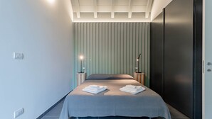 A modern bedroom with a bed, bedside lamps, and a wall-mounted panel. - TAGGIASCA (Taggia)