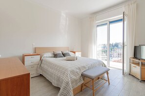 Ett sovrum med en säng, sängbord, ett skrivbord, en stol och en tv.