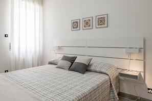 Ein modernes Schlafzimmer mit einem großen Bett, Nachttischlampen und Wanddekoration.
