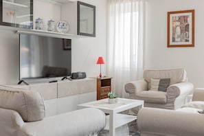 Ein modernes Wohnzimmer mit einer Couch, einem Couchtisch, einer roten Lampe und einer Küchenzeile mit Spiegel und Dekorationselementen.