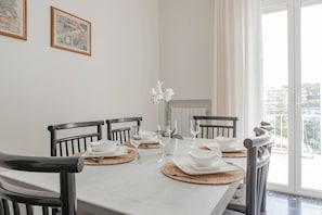 Een eettafel gedekt met witte borden, kommen en wijnglazen, omringd door zwarte stoelen.