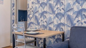 Ein Essbereich mit einem Tisch für zwei Personen, einem Stuhl und einem blauen Sofa.