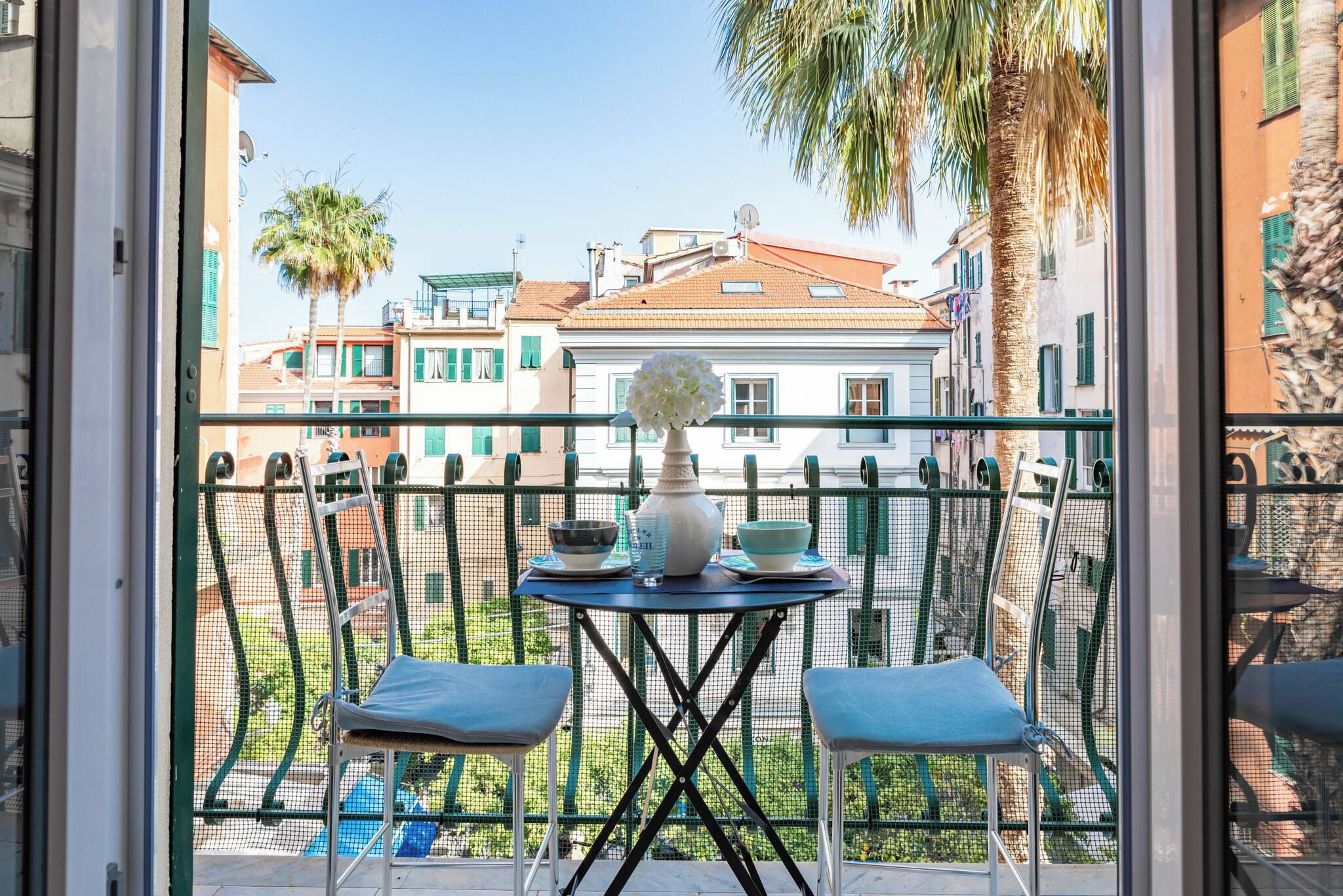 A balcony with a table, two chairs, and a vase of flowers.