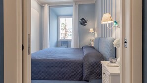 Ein Schlafzimmer mit Bett, Nachttisch, Lampe und Blick ins Freie.