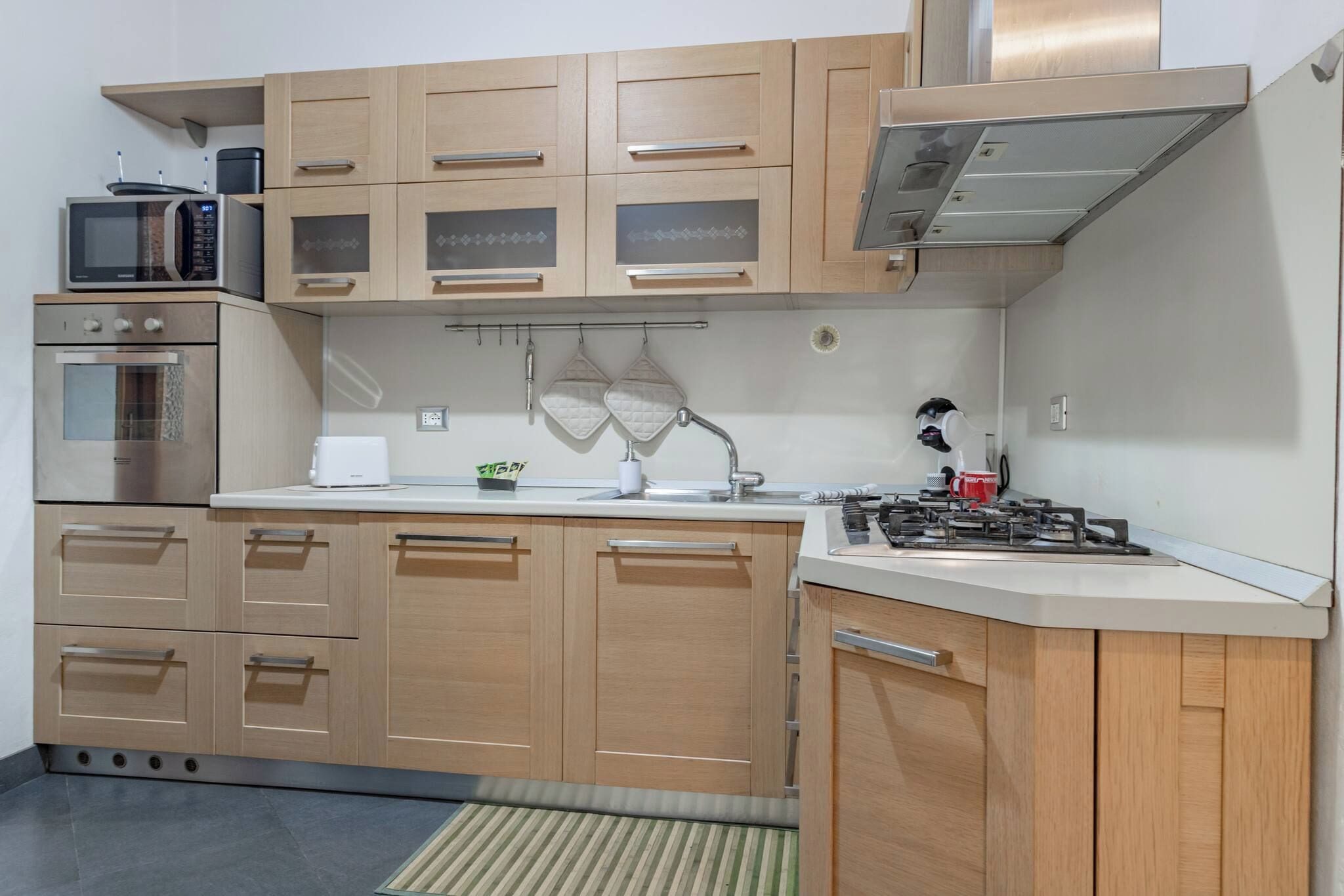 A modern kitchen with wooden cabinets, a microwave, an oven, a sink, and a gas stove.