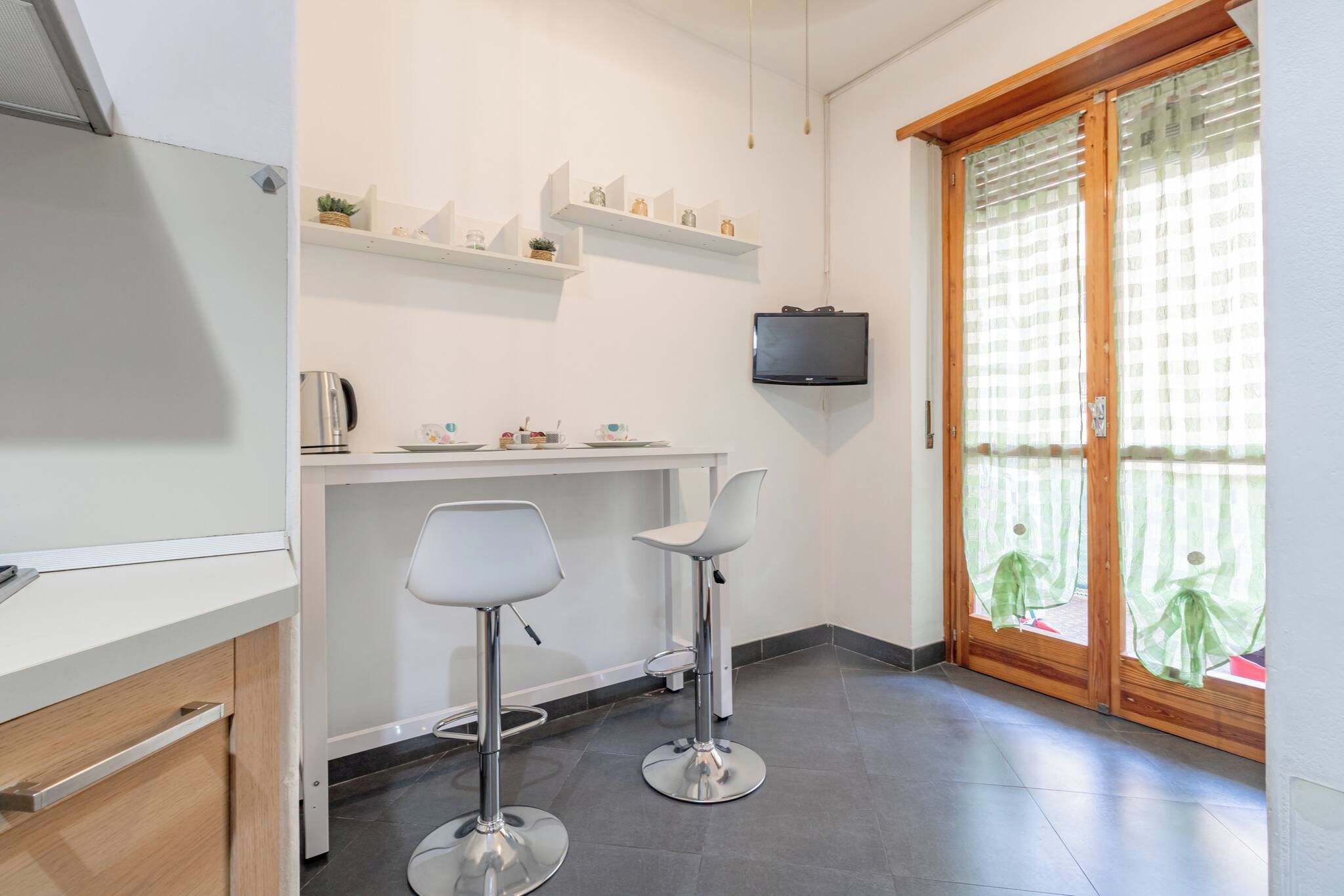 Une cuisine moderne équipée d’un téléviseur encastré, de deux tabourets de bar et d’une table à manger.