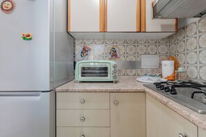 A kitchen with a vintage toaster, a refrigerator, a stove, and decorative wall tiles. - CATTY'S HOUSE - Mare - Parcheggio (Santo Stefano al Mare)