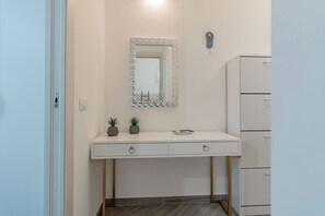 A bathroom with a white vanity, a mirror with a mosaic frame, a towel rack with a starfish, and a cabinet with drawers. - CASA ALICE - Monolocale - Sanremo (Sanremo)