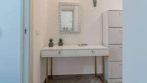 Un mobile bagno bianco con due cassetti, uno specchio con cornice a mosaico e due piante in vaso.