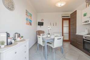 A modern kitchen with white cabinetry, a built-in oven, and a dining area with a table and chairs. - ELENA HOUSE - Vista - Porto (Sanremo)