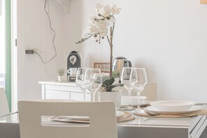 A dining area with a table set for two, featuring a coffee maker, a clock, and a potted plant. - ELENA HOUSE - Vista - Porto (Sanremo)